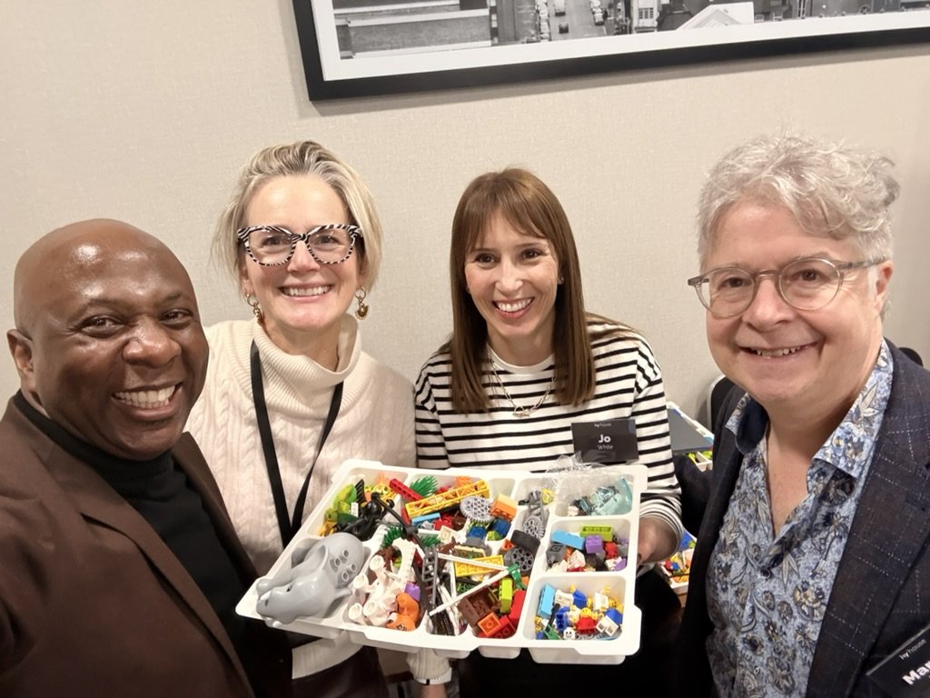 Robert Stephenson and workshop participants gathered around a tray of building blocks used in an experiential facilitation exercise